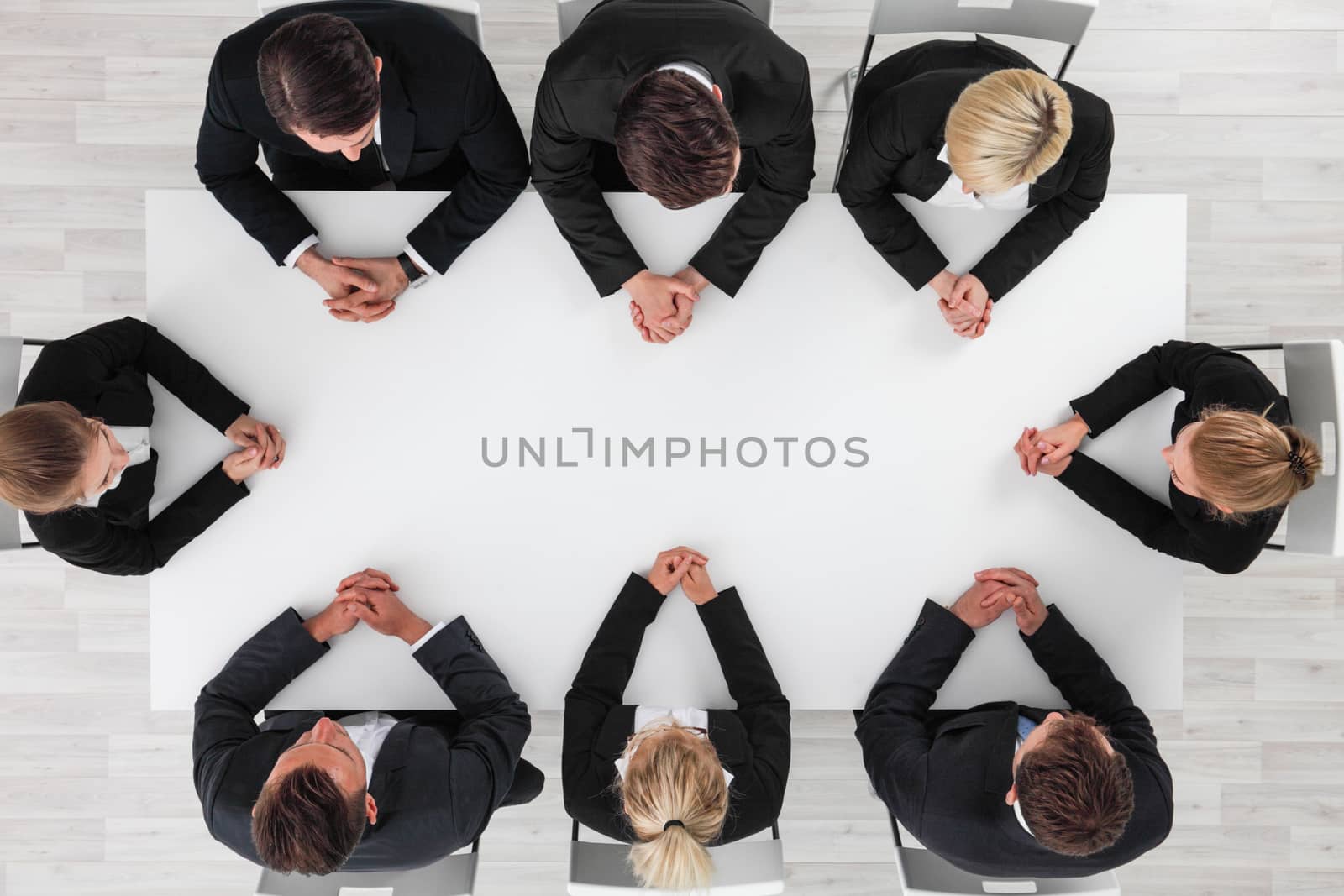 Business people sitting around empty table, blank copy space in the middle