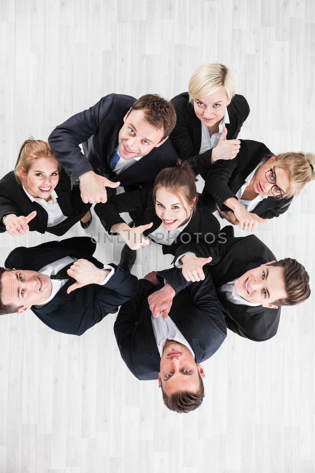 Young group of business people showing thumbs up signs in joy, top view with copy space