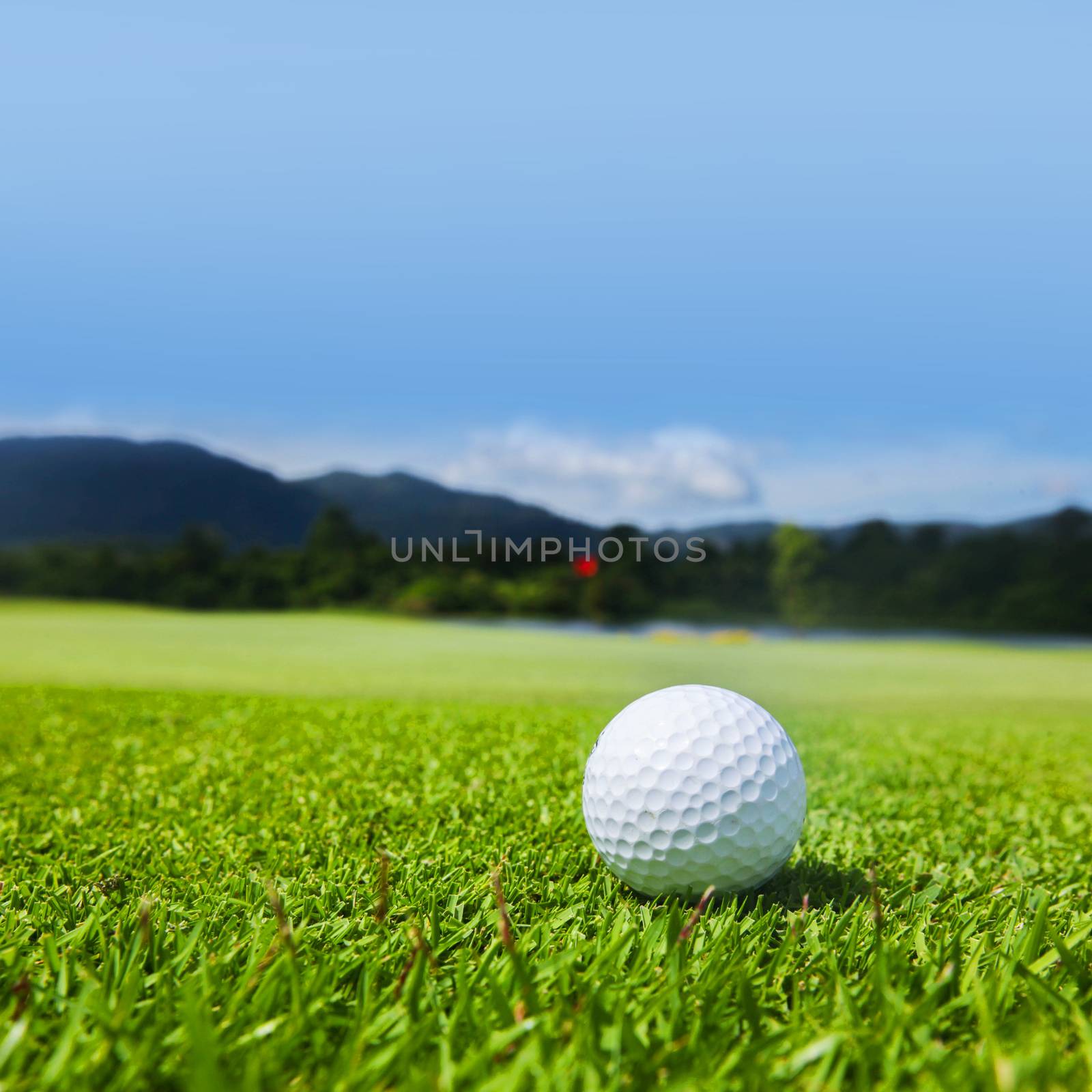 Golf ball on course, beautiful landscape with mountains on background