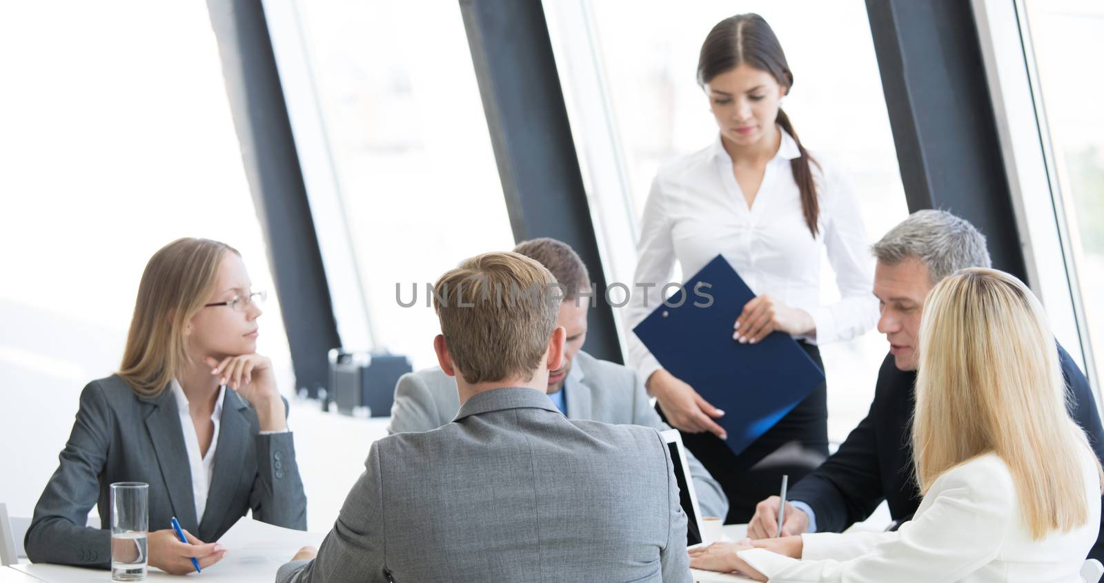 Business person group in formalwear discuss documents at meeting in modern office