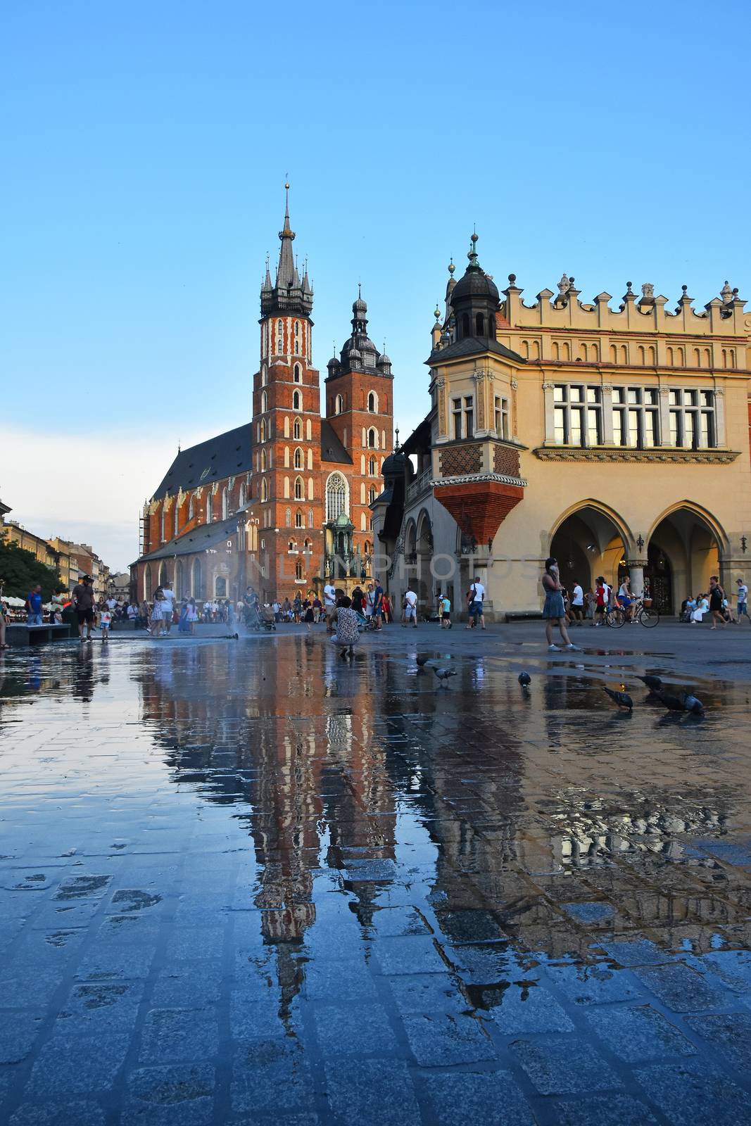 Low angle view of Main Market Square with town hall and Church of Our Lady Assumed into Heaven (Saint Mary Church after rain in Krakow, Poland