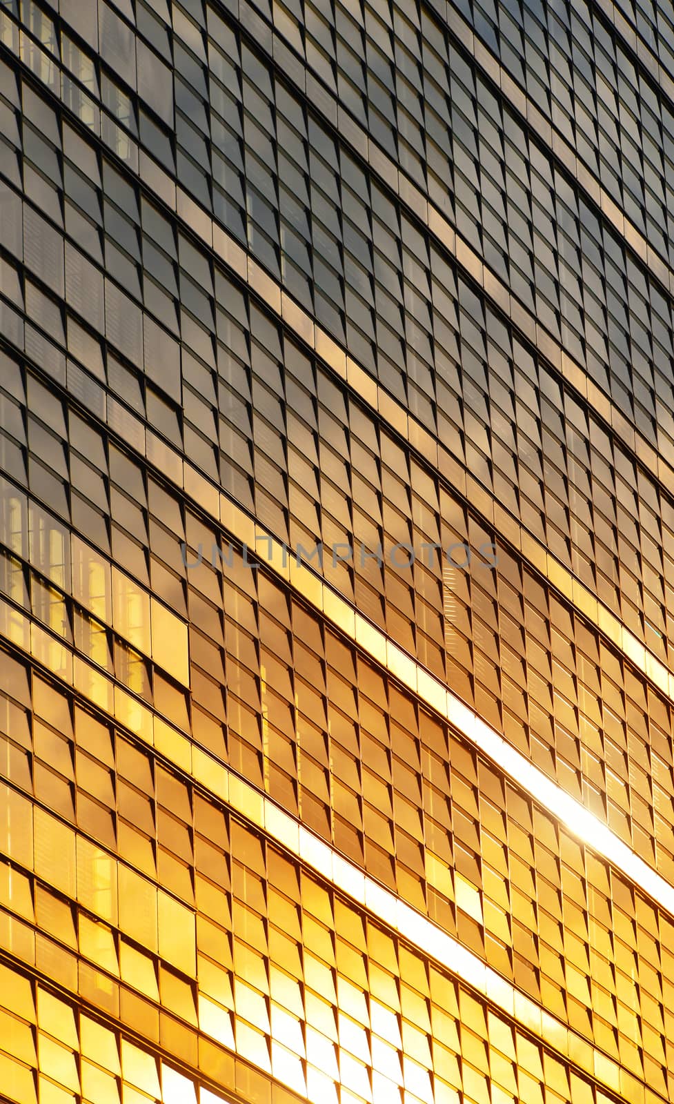 Orange colored glass windows of modern business office building at sunset in evening, diagonal perspective, low angle view