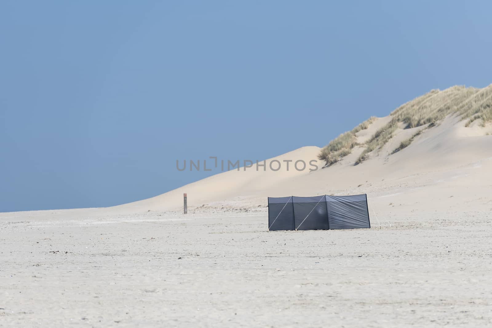 Wind screen on the beach with dunes on the background
