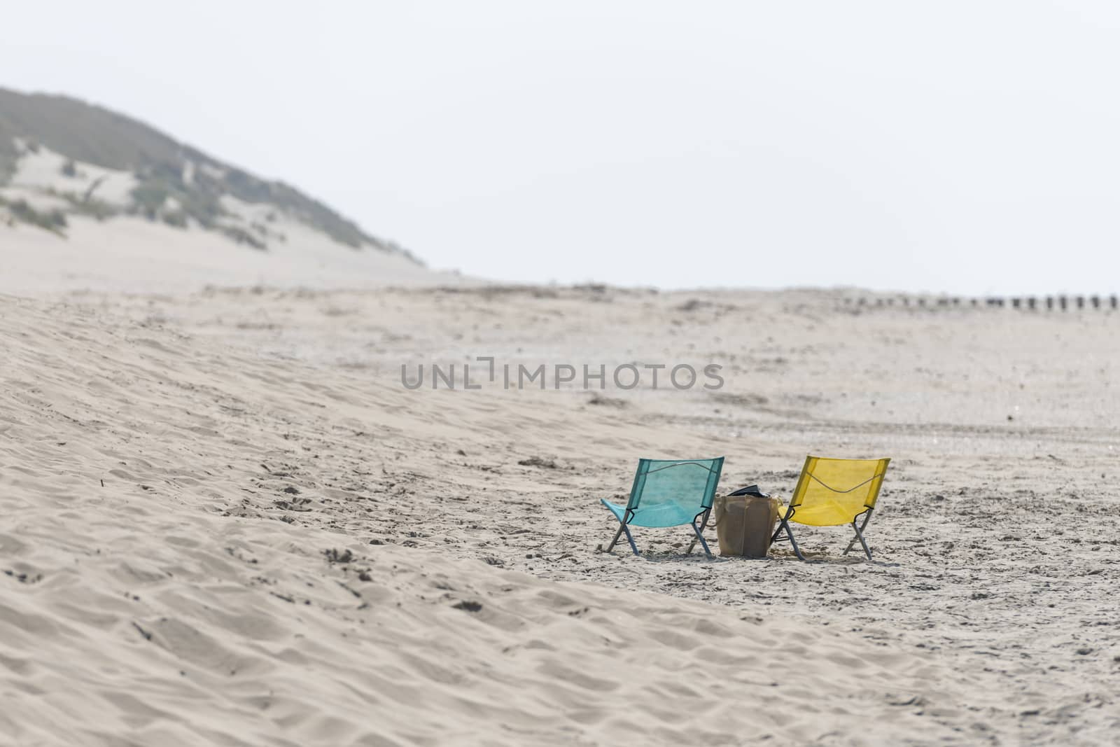 A blue and yellow folding chair on a beach
 by Tofotografie