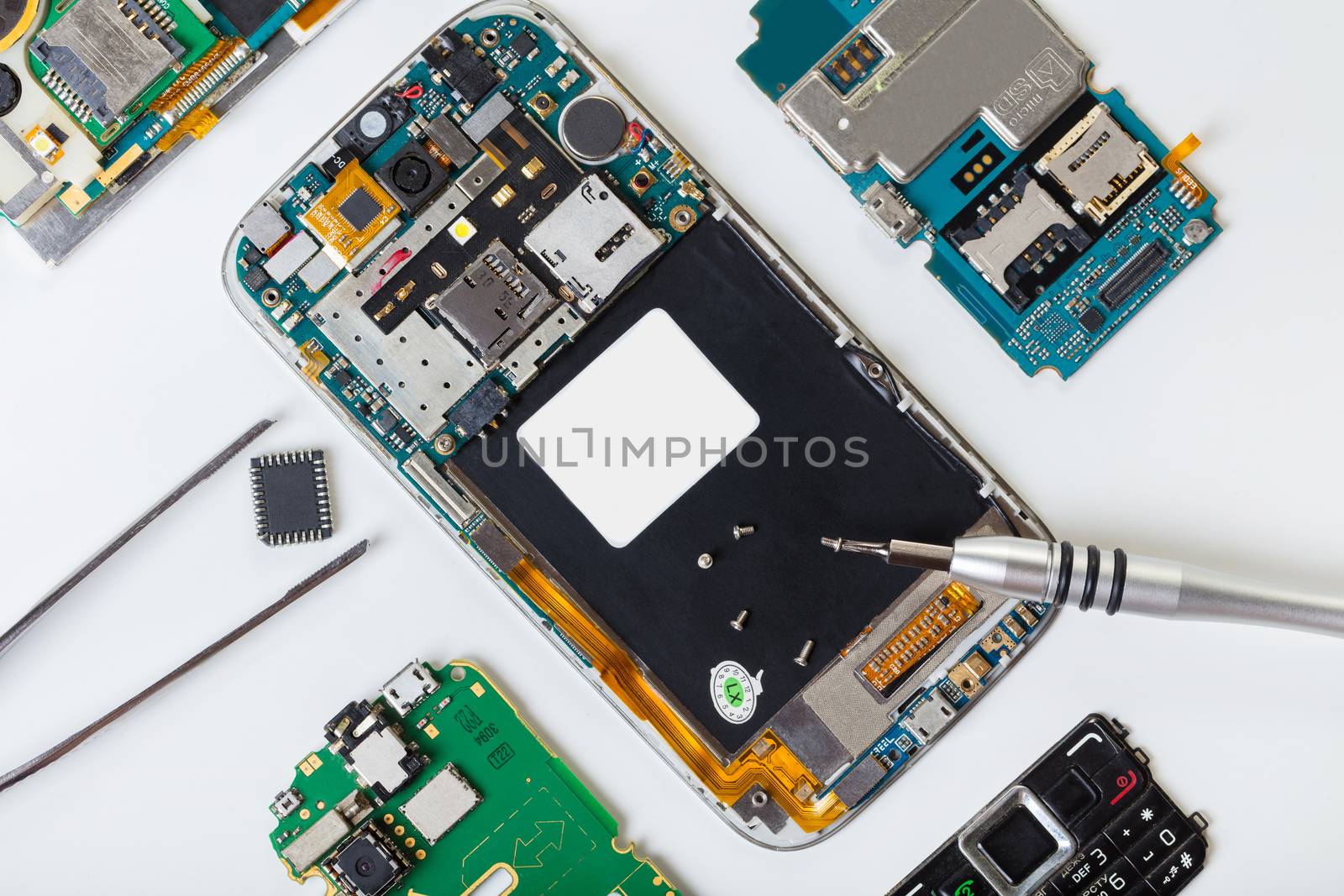 disassembled mobile phone and tools on white background