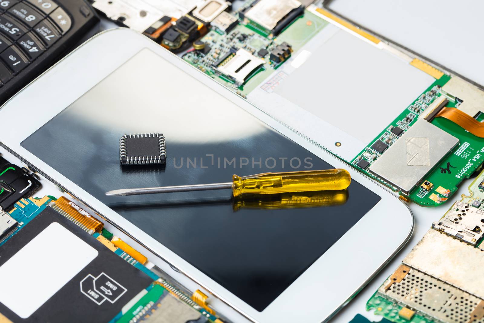 screwdriver on background of the disassembled mobile phone