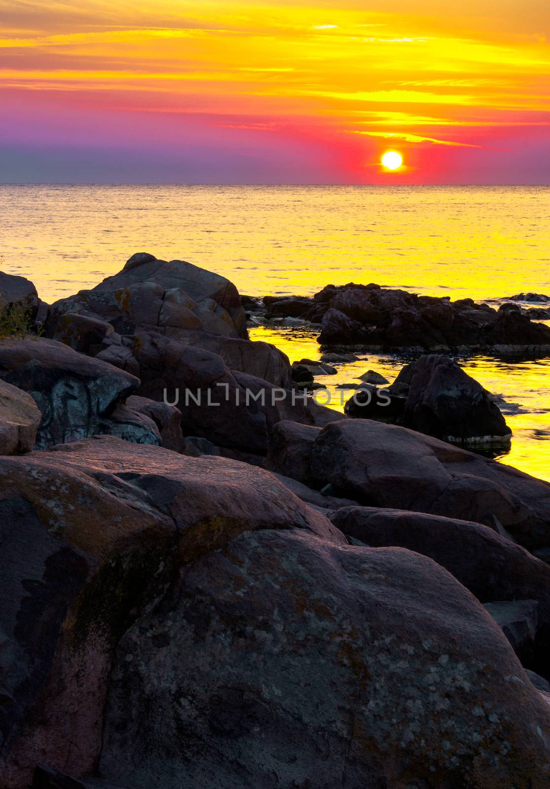 reddish sunrise over the sea with rocky shore. beautiful summer scenery and vacation concept