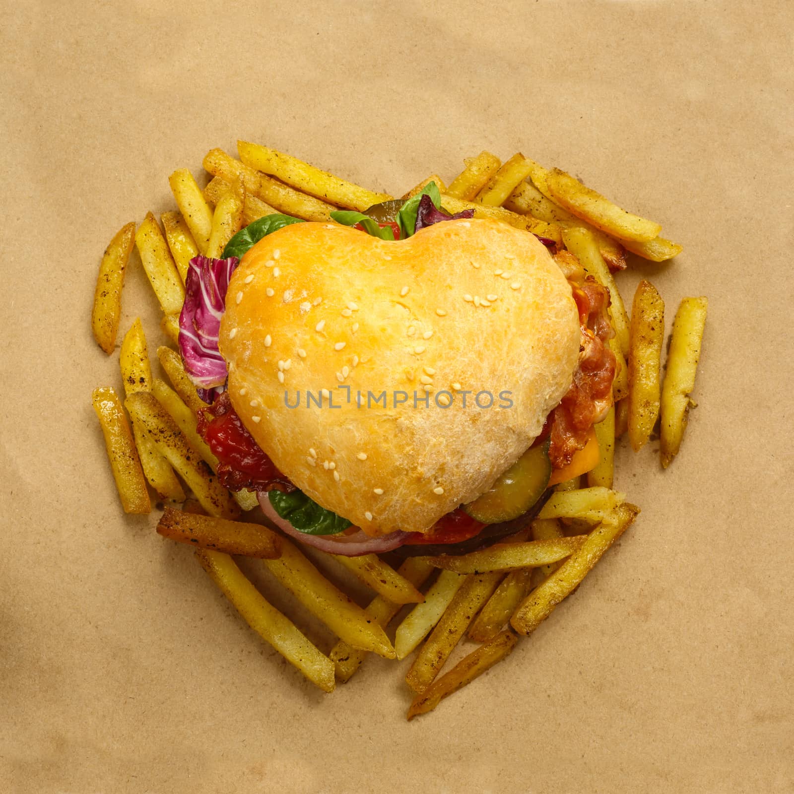 Heart shaped hamburger and french fries, love burger fast food concept, on brown paper background, top view