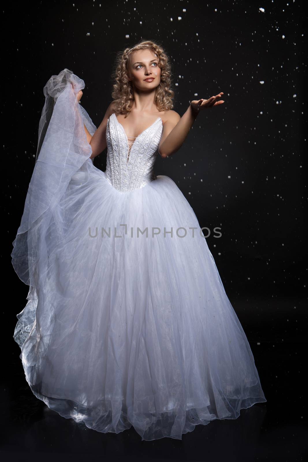 Young attractive woman in a wedding dress with a white violin on a studio background