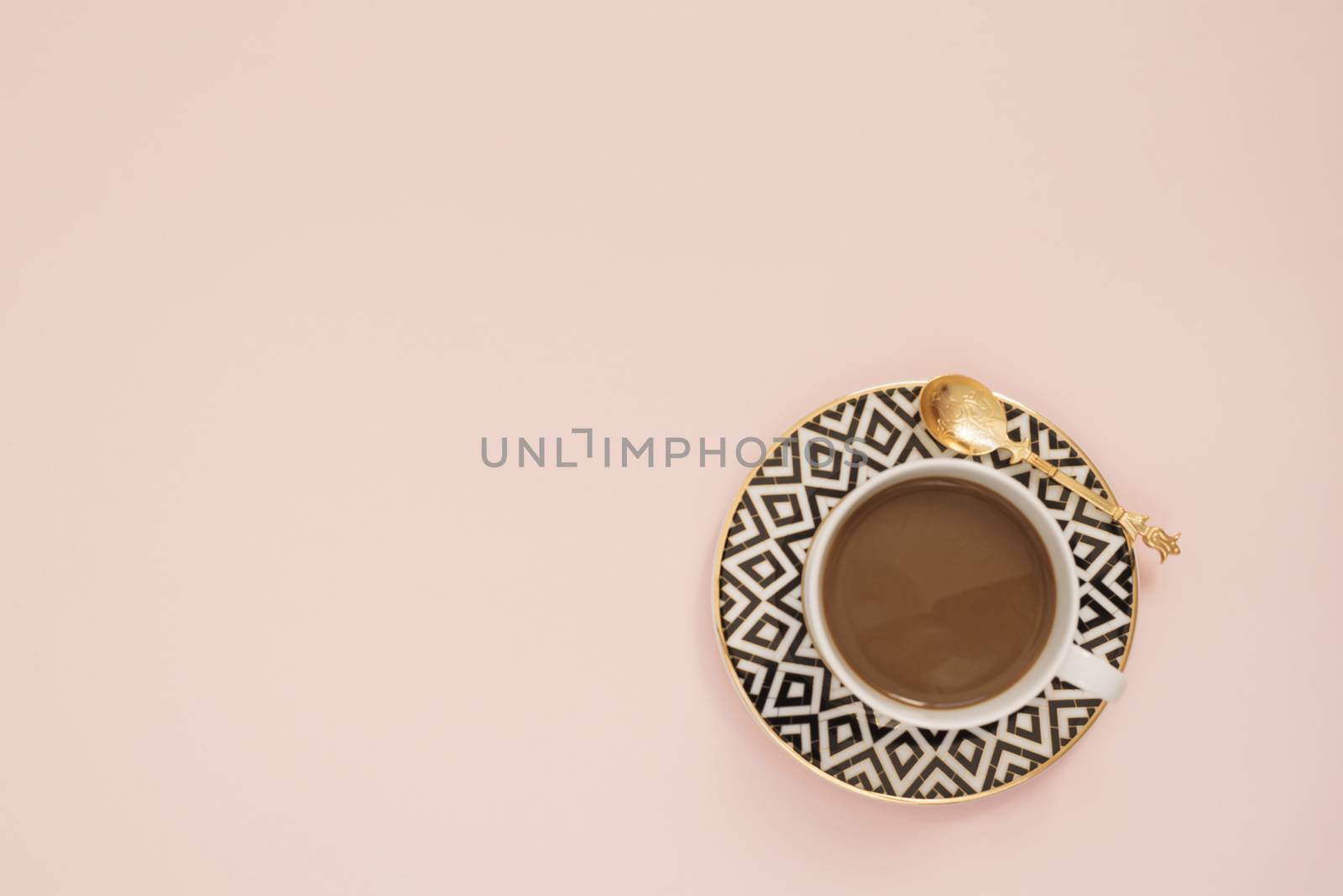 Coffee on a pastel punchy pink background.  Latte in a white, black and gold coffee cup. Feminine workplace concept. Freelance fashion comfortable femininity workspace with coffee.