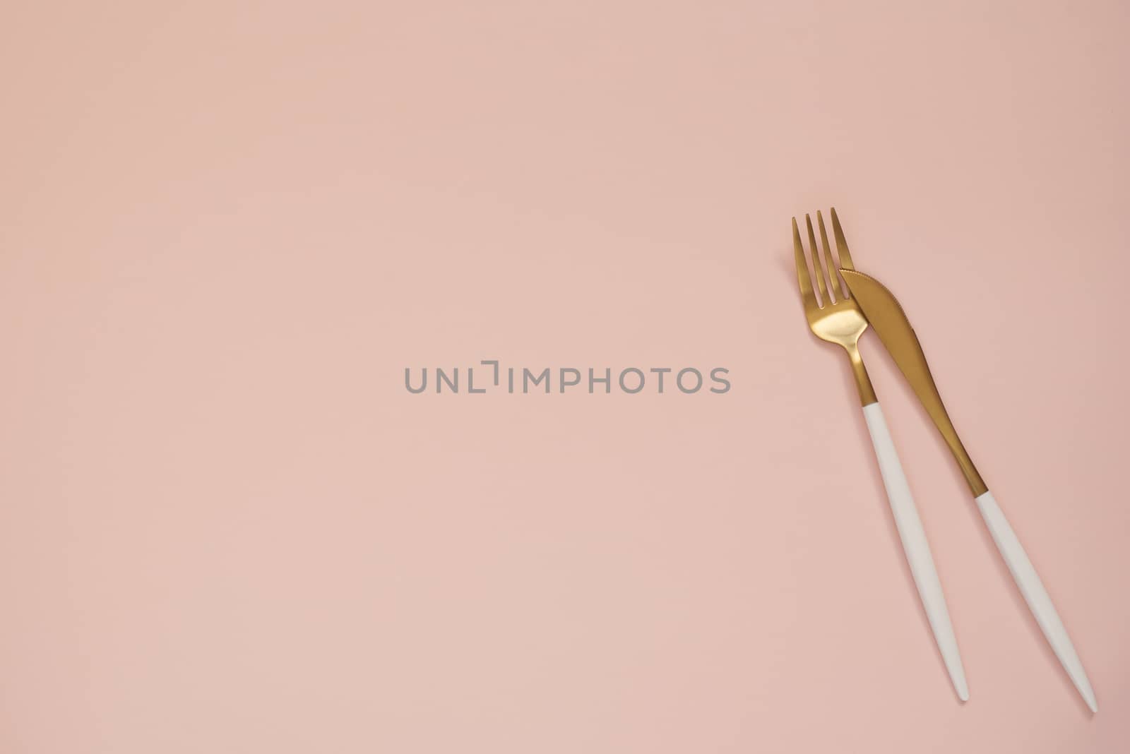 Gold cutlery. Golden spoon set, golden knife and fork on the table. Luxury spoon set top of view. Pastel punchy pink background 