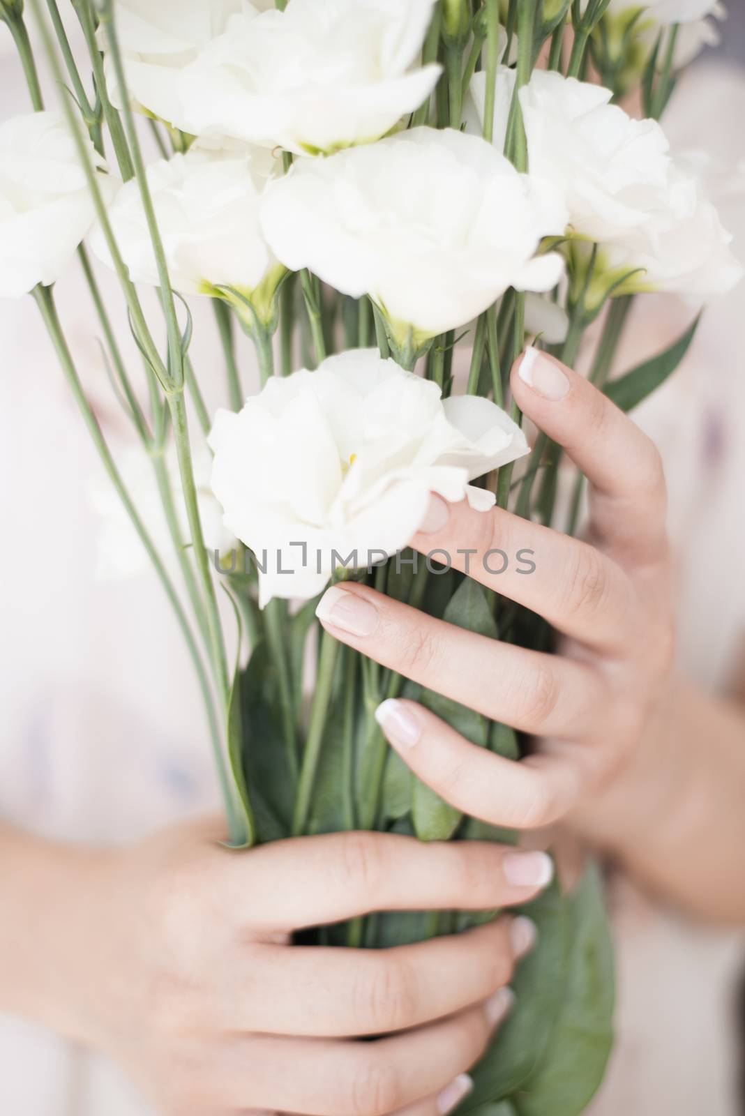 A young girl hand holding a large bouquet of fresh white flowers. Bright feminine lifestyle