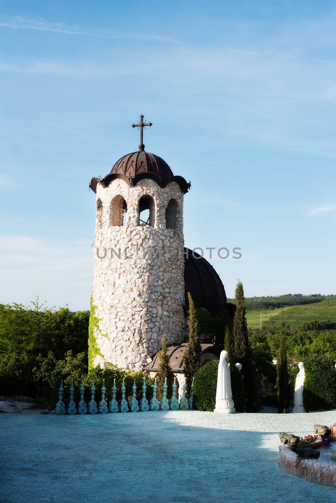 Old stone chapel in the garden of fabulous ancient castle. Alley in beautiful garden with flowers and trees around. Summer in the garden