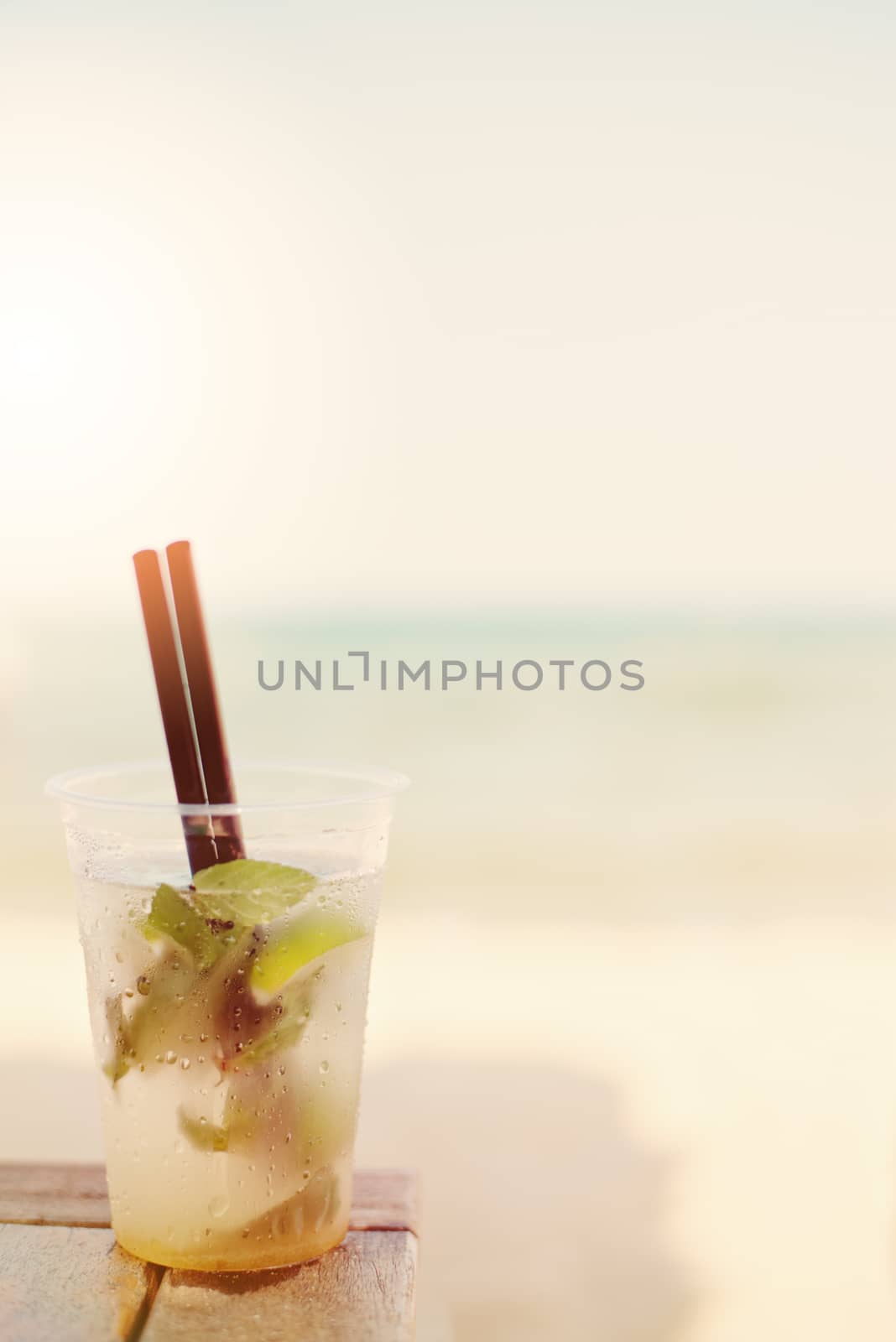 Mojito cocktail on the beach, blurred beach background. Sun, sun haze, glare