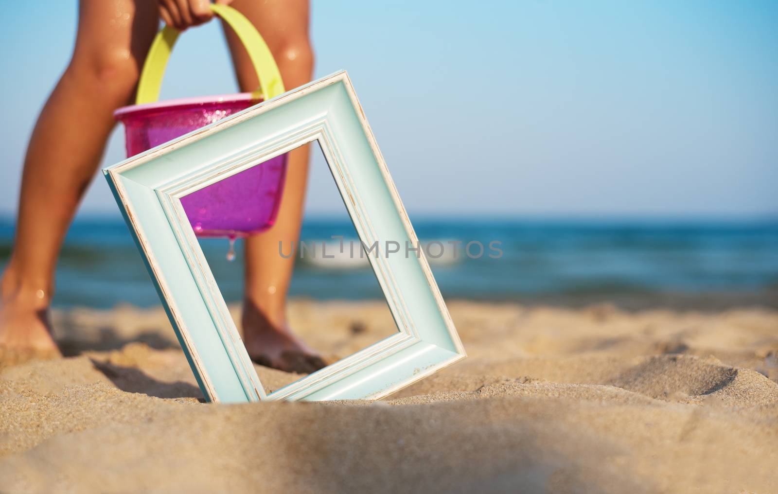 Wooden picture frame on the beach sand, summer concept. Children play in the sand beach