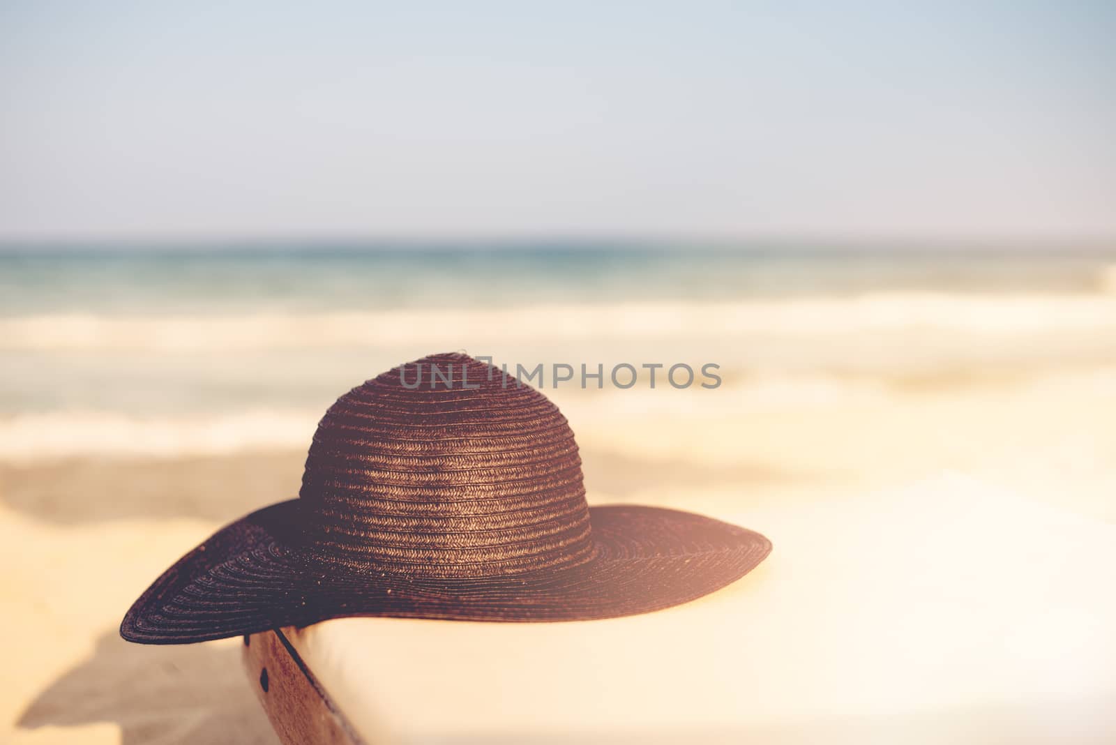 Black Hat on Beach Chair On The Tropical Sand Beach. Sun, sun haze, glare. Copy space