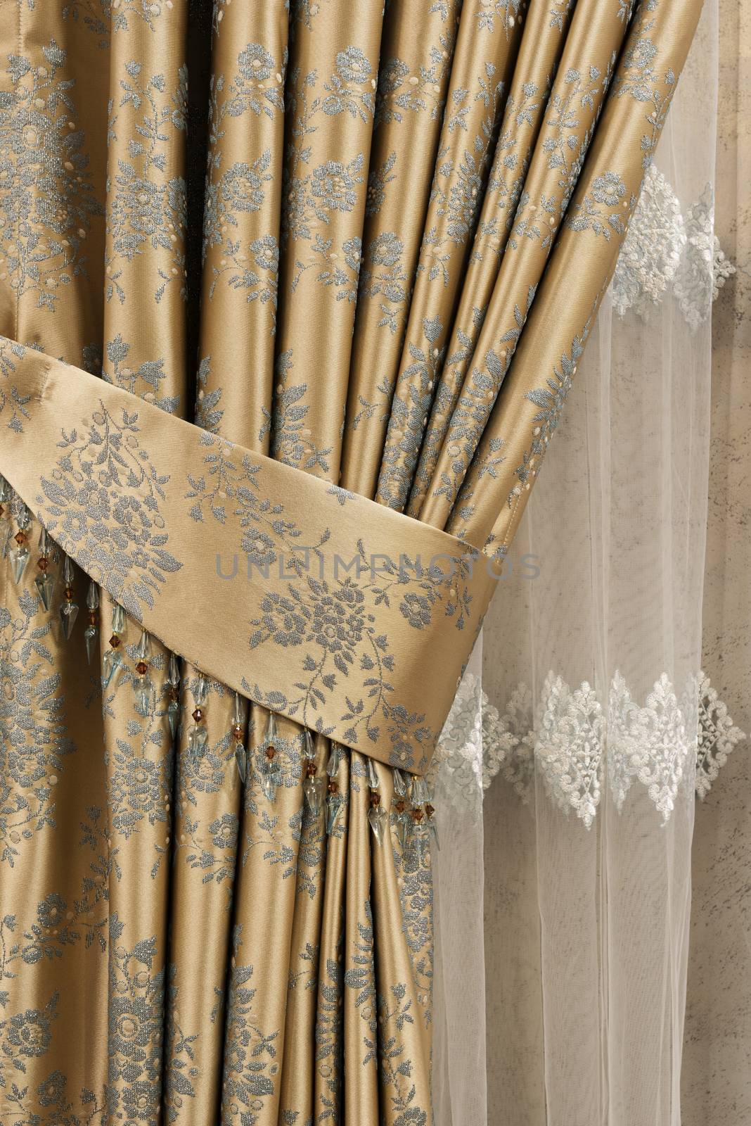 Part of beautifully draped curtain on the window in the room. Close up of piled curtain. Gold luxury curtain, home decor