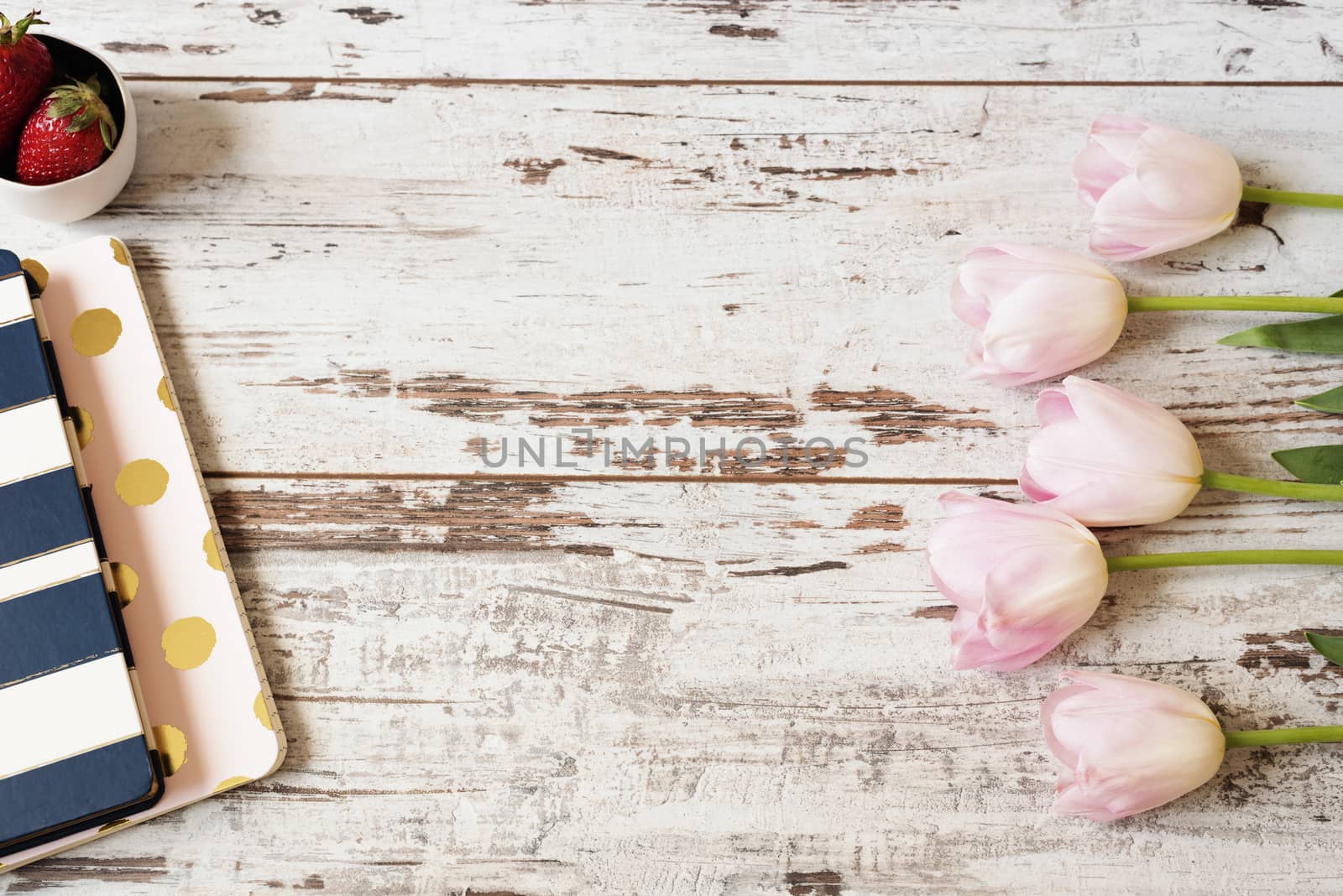 Stunning pink tulips, stripe notebooks and strawberries on white light rustic wooden background. Copy space, floral frame. Wedding, gift card, valentine's day or mothers day background