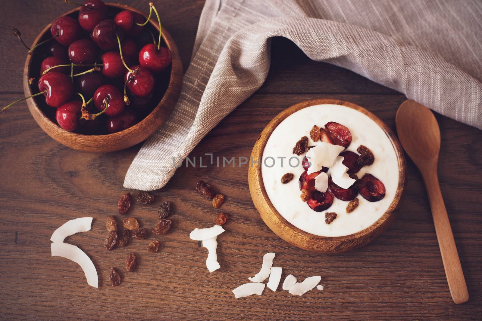 Oat Flakes With Yogurt And Fruits. Cherries, Raisins And Coconut Chips. Overnight Breakfast. Healthy Food Concept. Fitness Mood Diet. Summer Light Snack. Dark Wooden Background. Fawn Filter