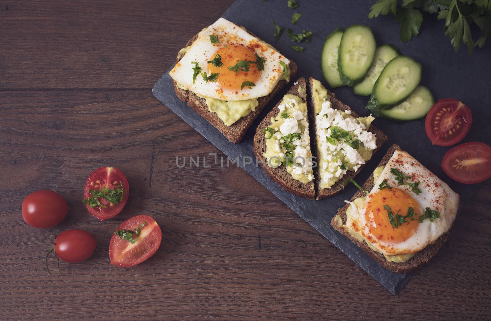 Avocado Toast. Healthy Breakfast. Top View. Homemade Sandwich With Avocado And Fried Eggs, Cherry Tomato And Cucumbers On A Wooden Background. Dark Food Photography, Fawn Filter