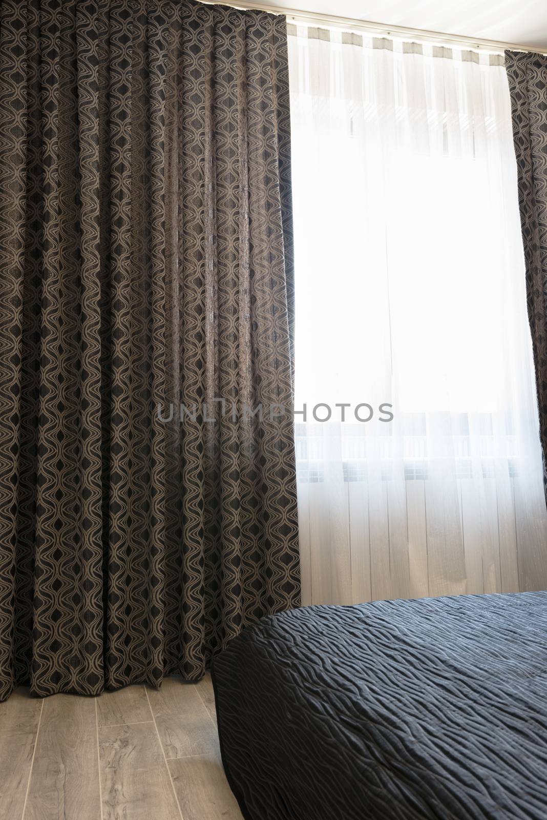 Long dark luxury curtains and tulle curtains, sheers on a window in the bedroom. Interior design concept
