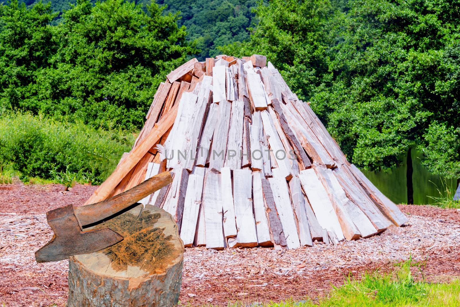 Conical stacked logs, firewood storage for the winter. In the foreground a hack wood with ax.