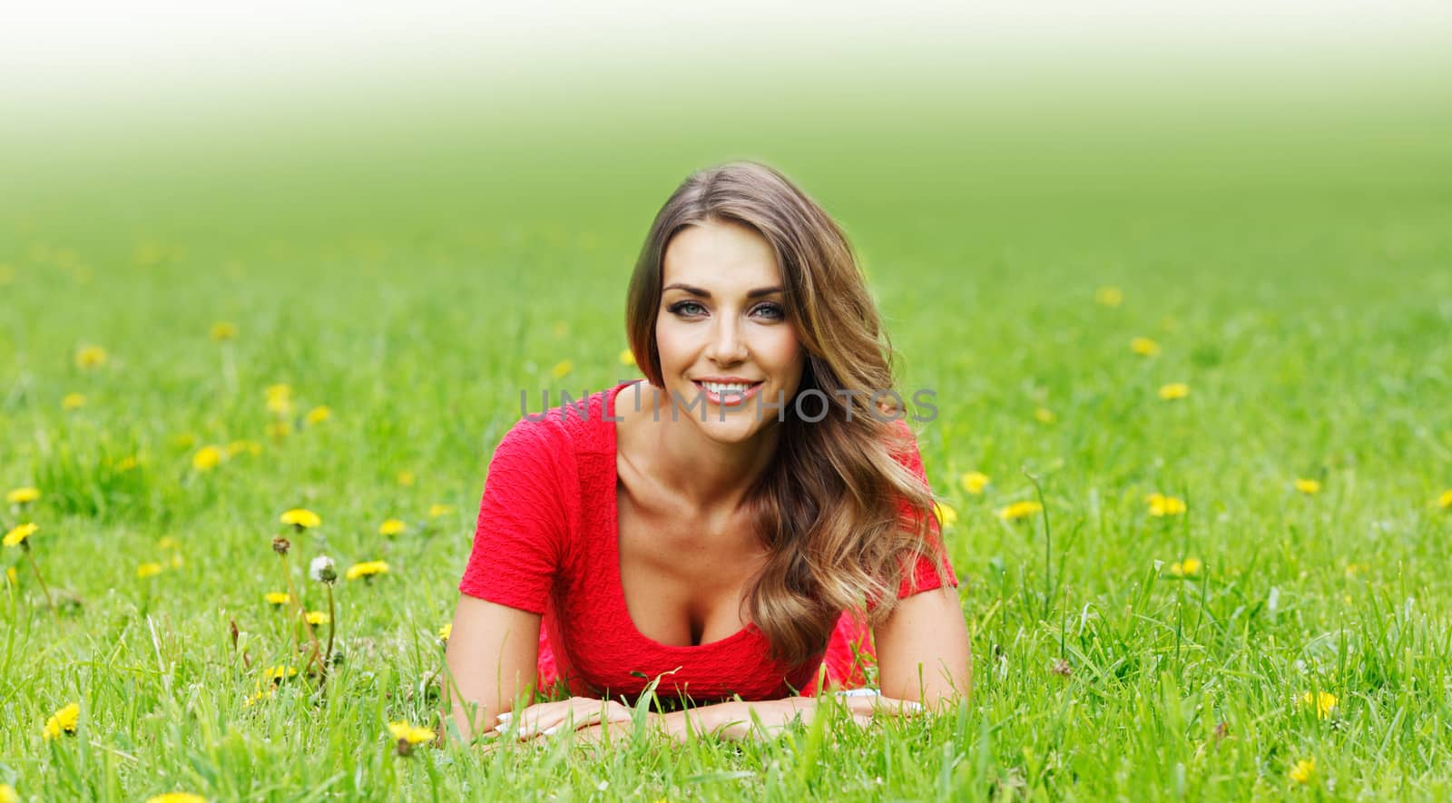 beautiful young woman in red dress lying on grass
