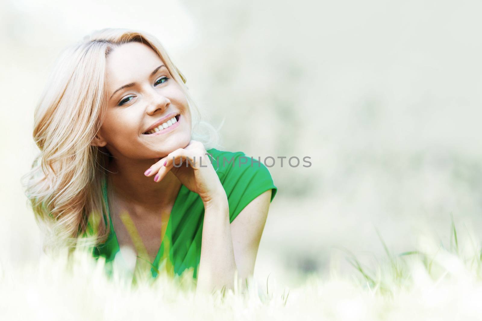 Young beautiful woman enjoying laying on fresh green grass