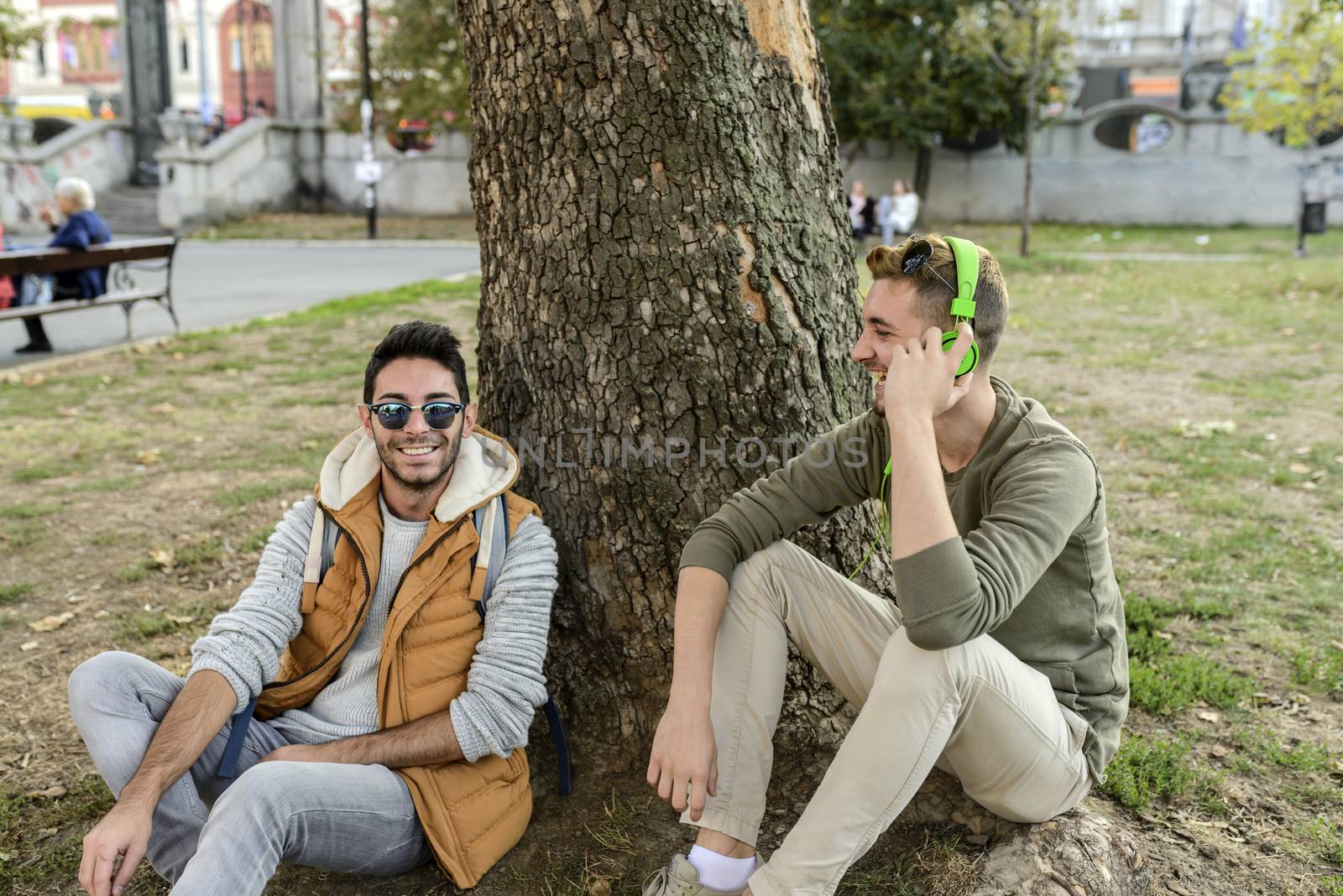 Two friends relaxing under the tree in the public park