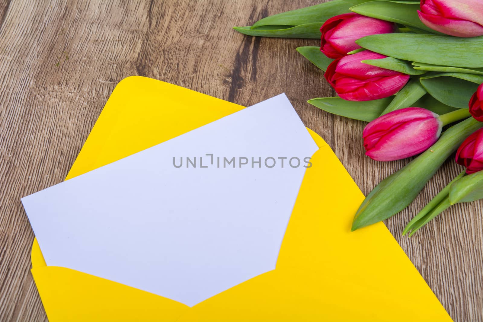 Yellow envelope with tulips on a wooden table