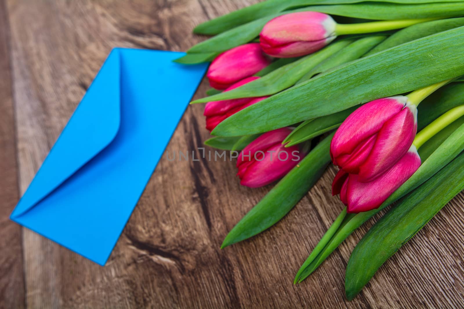 Blue envelope with tulips on a wooden table