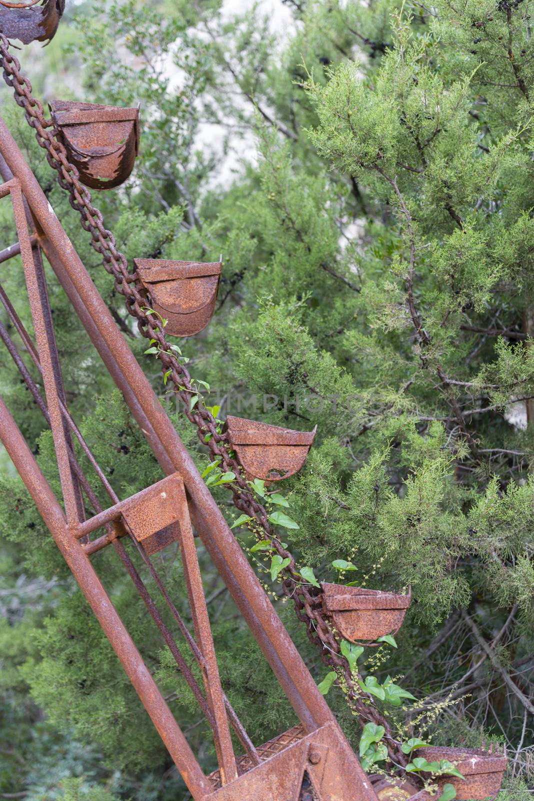 exterior of old mining factory with rusty conveyor belts with buckets on the island of sardinia near golfo aranci