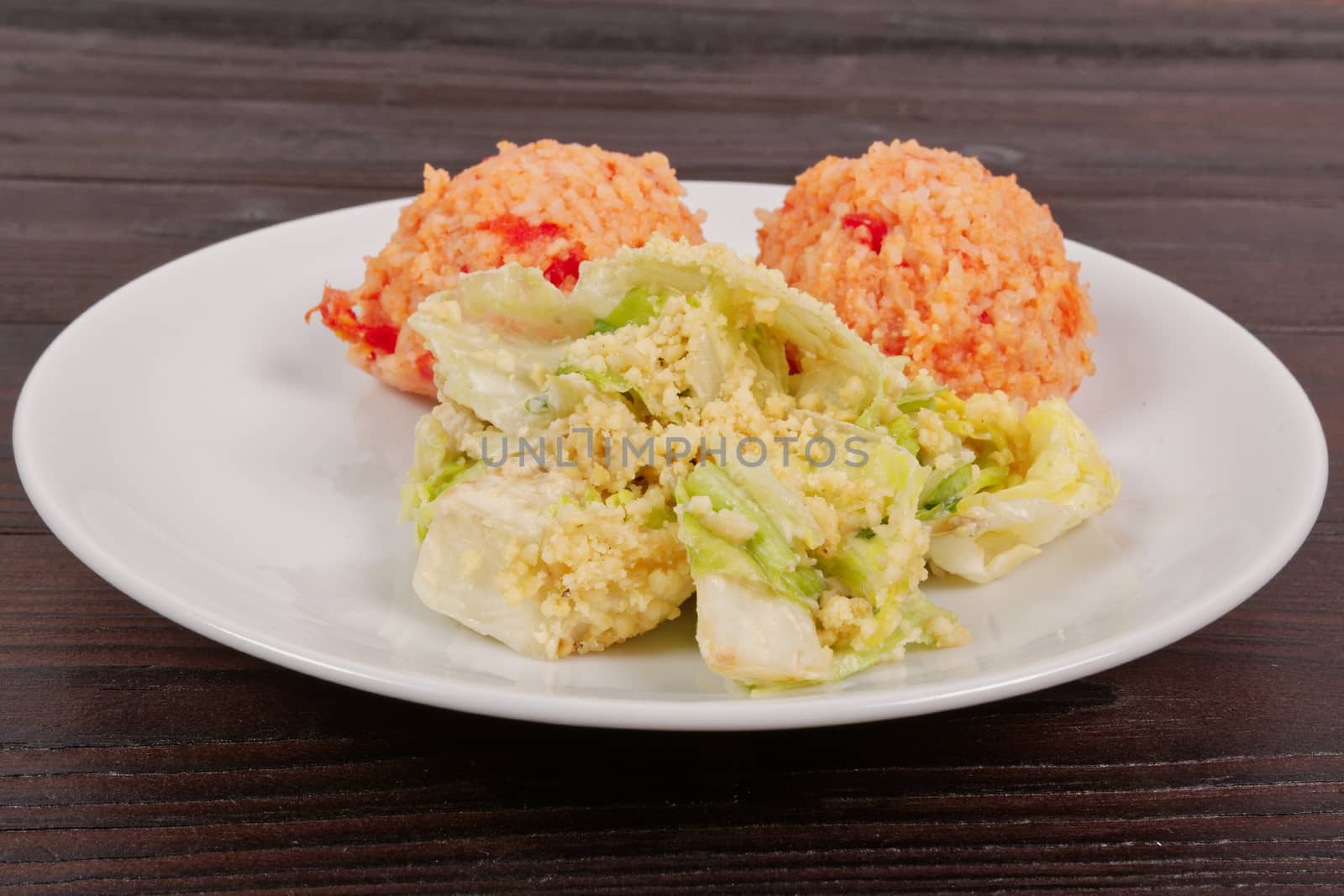 Tomato rice and salad on a wooden table