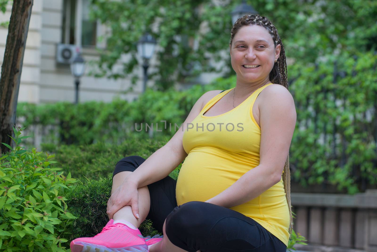 Happy smiling pregnant woman sitting outdoors, spring or summer time.