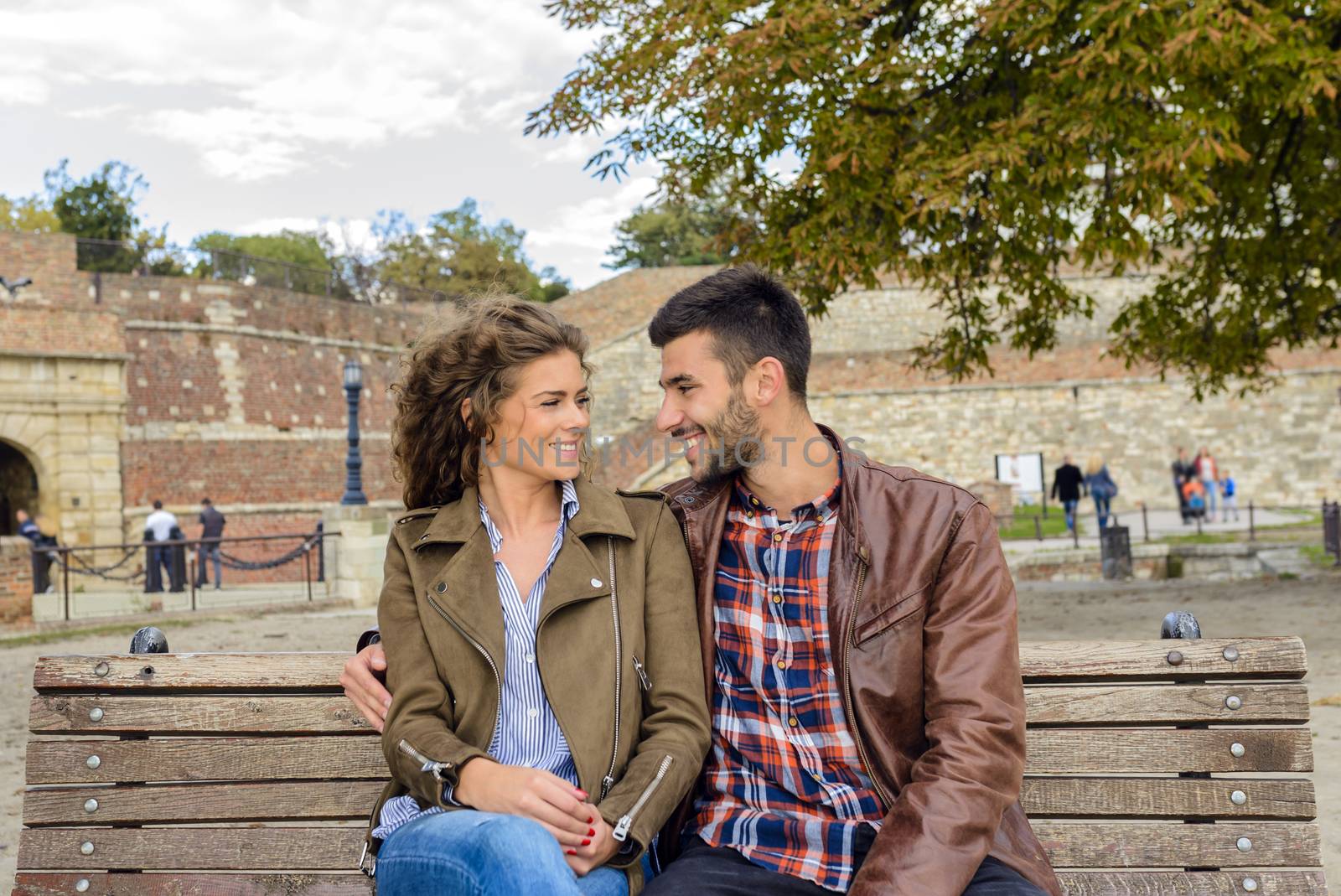 Attractive couple in love enjoying moments of happiness on the bench in city park