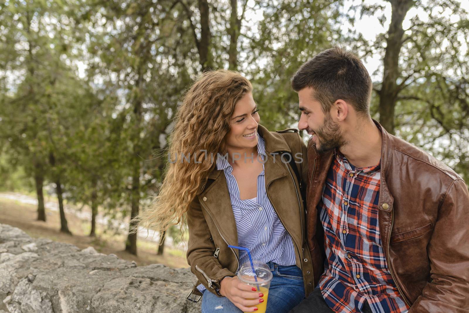 Attractive couple refreshing in the park by VeraAgency
