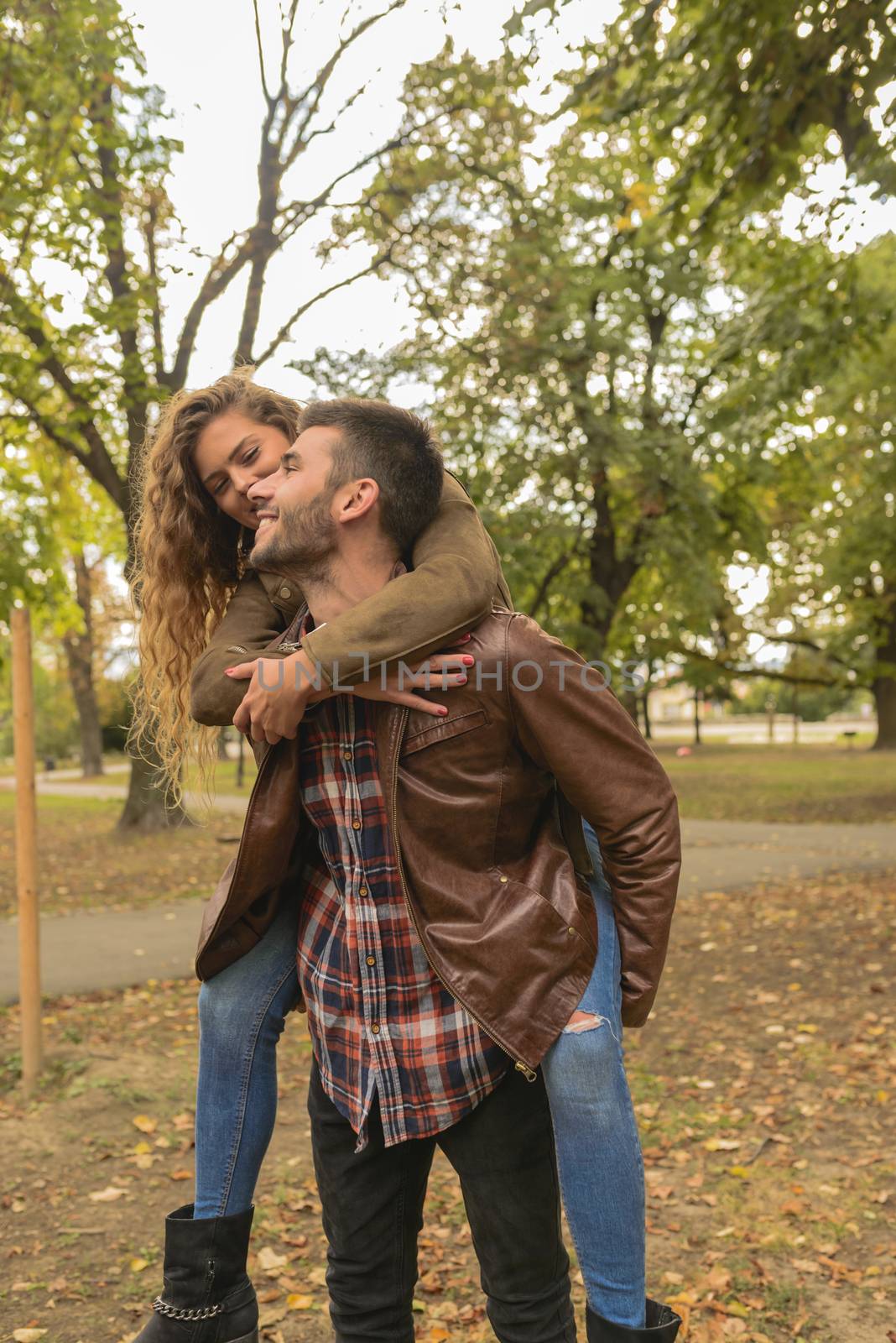 Handsome man carrying his attractive girlfriend on the back by VeraAgency