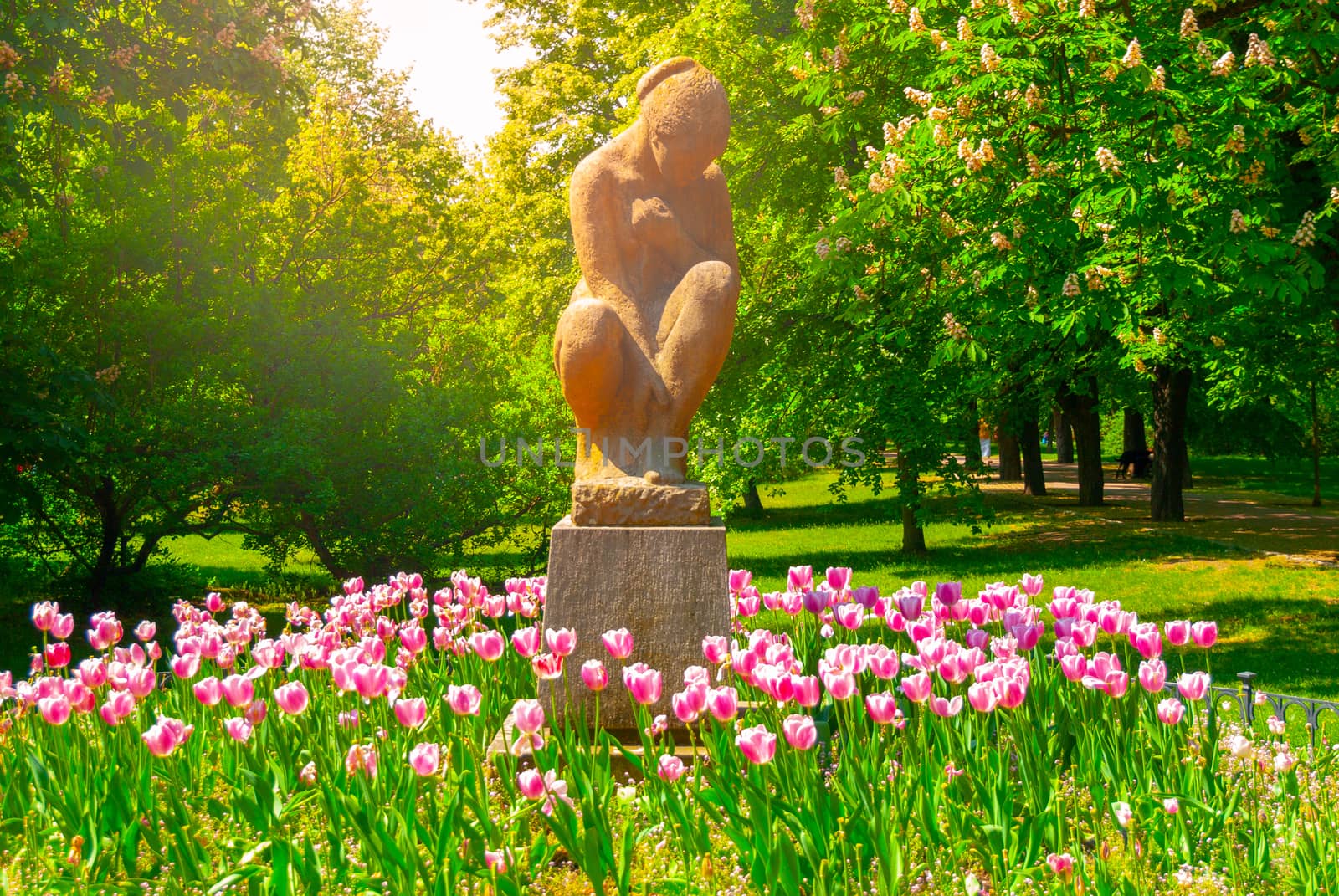 Sculpture of seated woman in Letna Park on sunny summer day with pitnk tulips, Prague, Czech Republic.