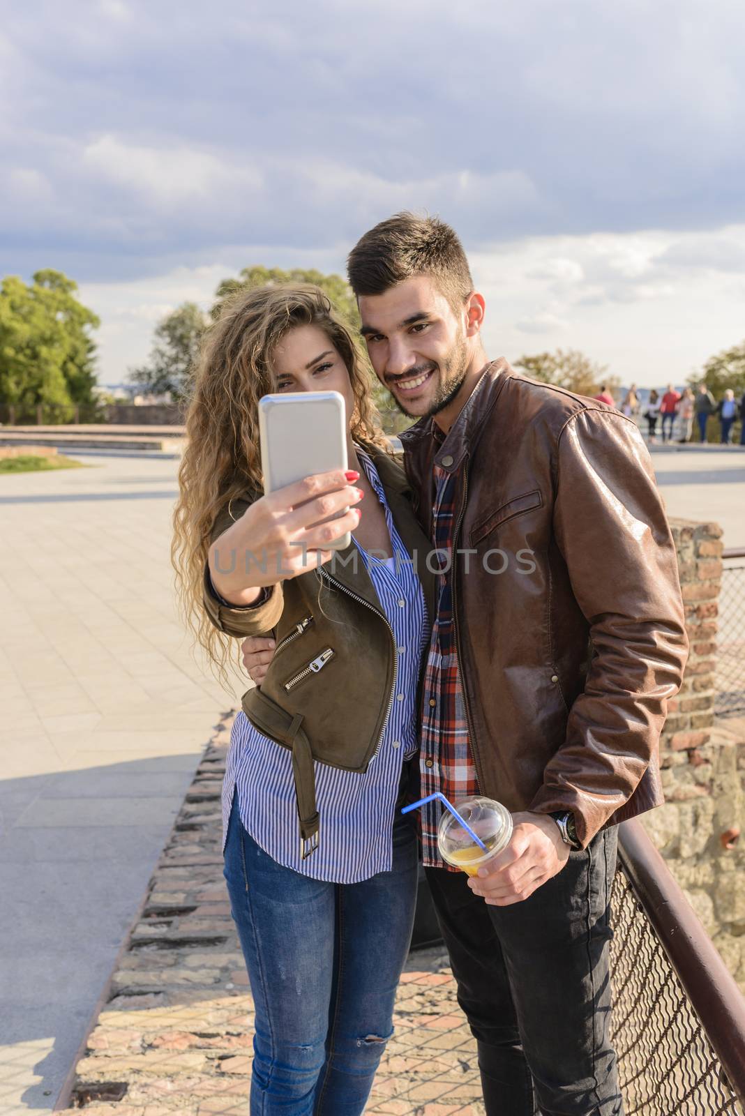 Long haired young woman enjoying the time by taking selfie with her handsome boyfriend