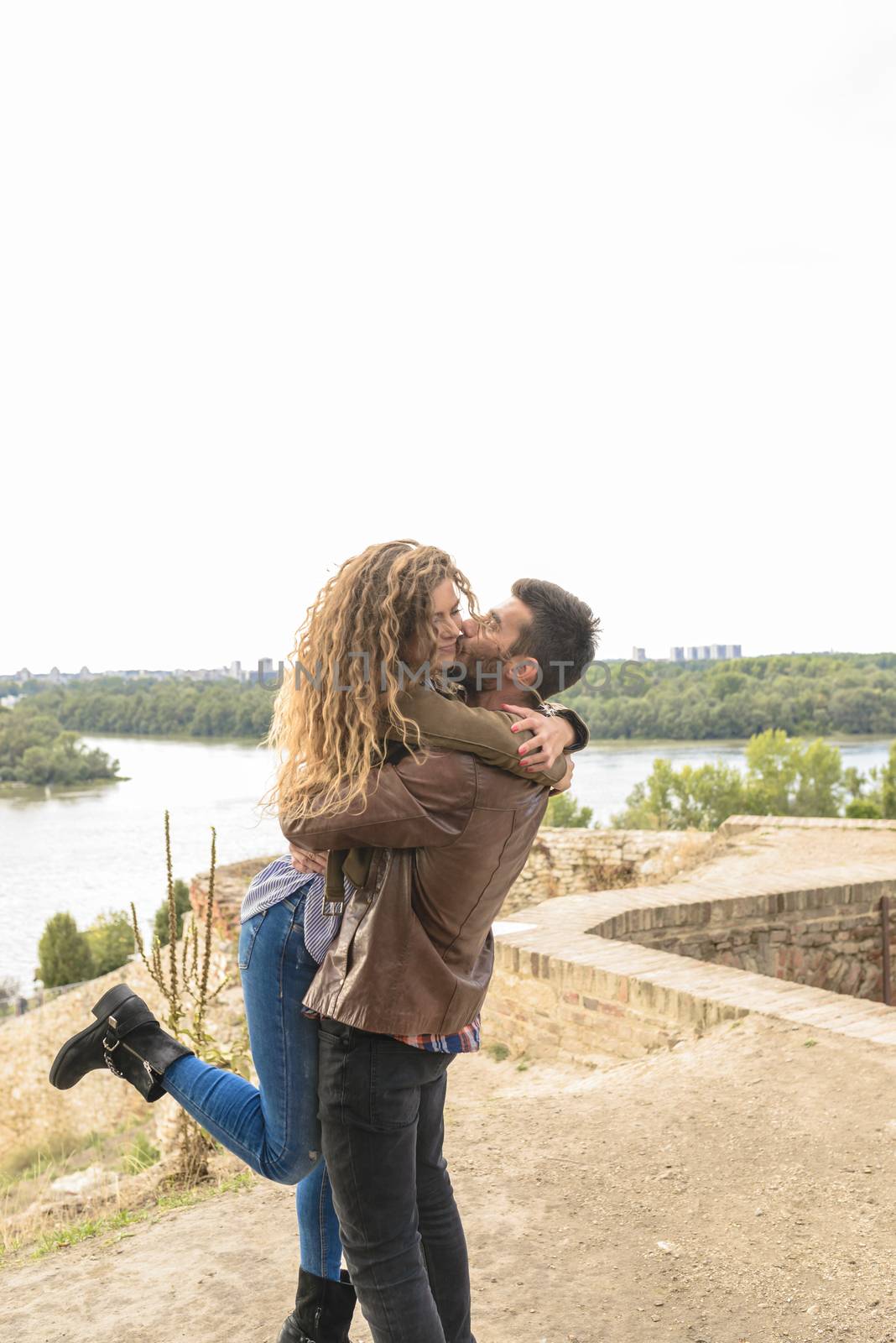 Attractive long haired girl is hugging his boyfriend while he is kissing her