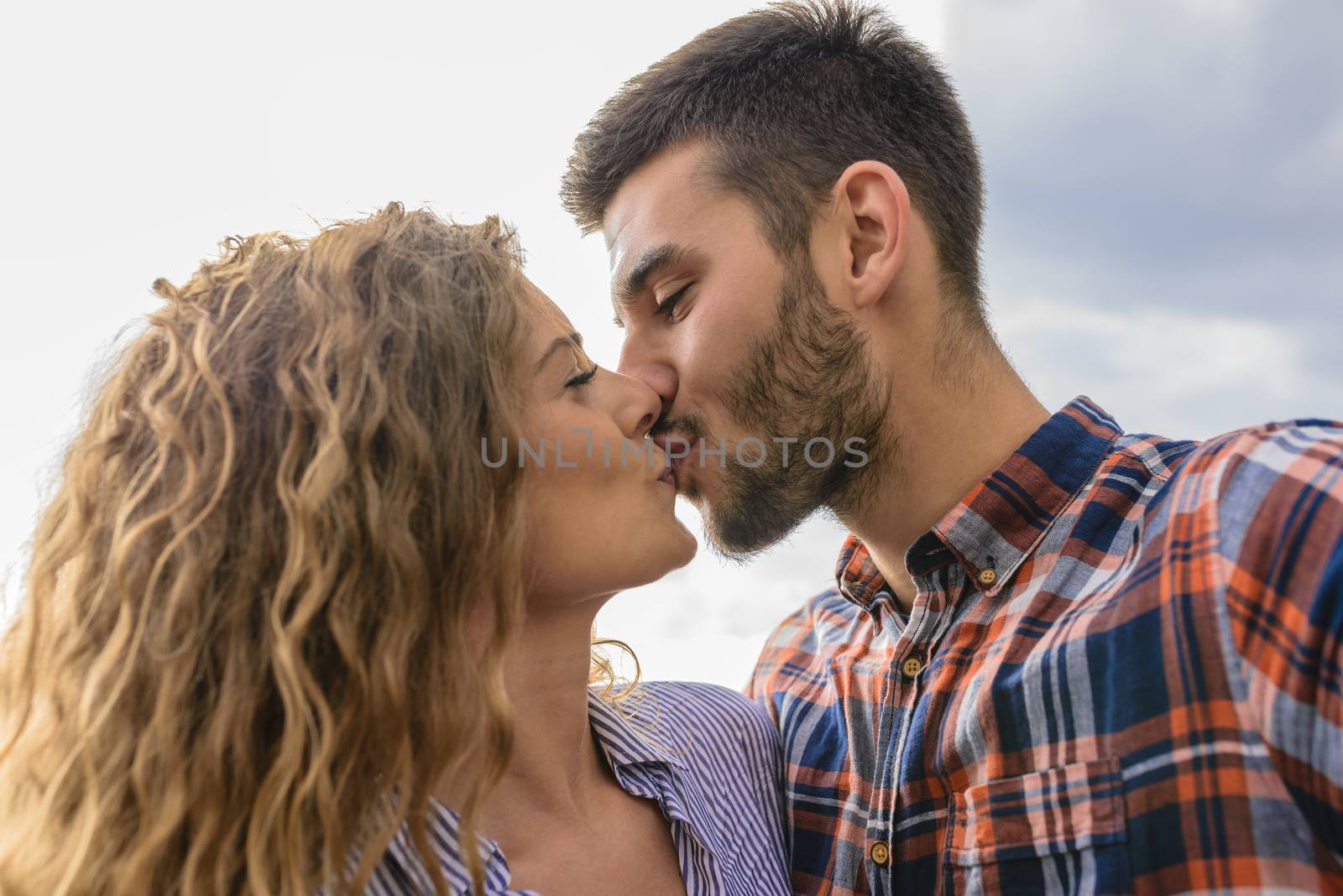 Attractive and modern lovers kissing in the nature