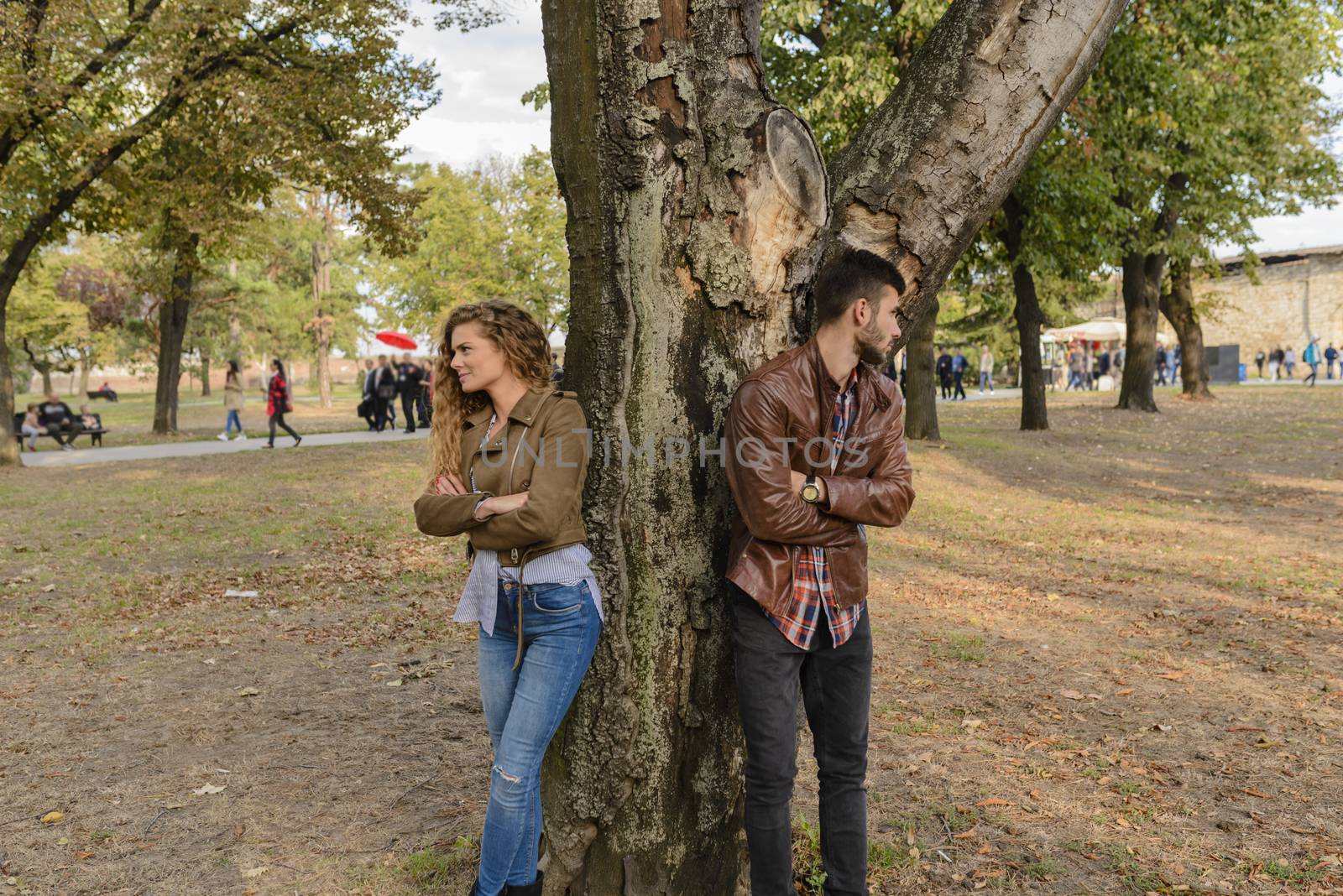 Young couple ignoring each other in the public park by VeraAgency