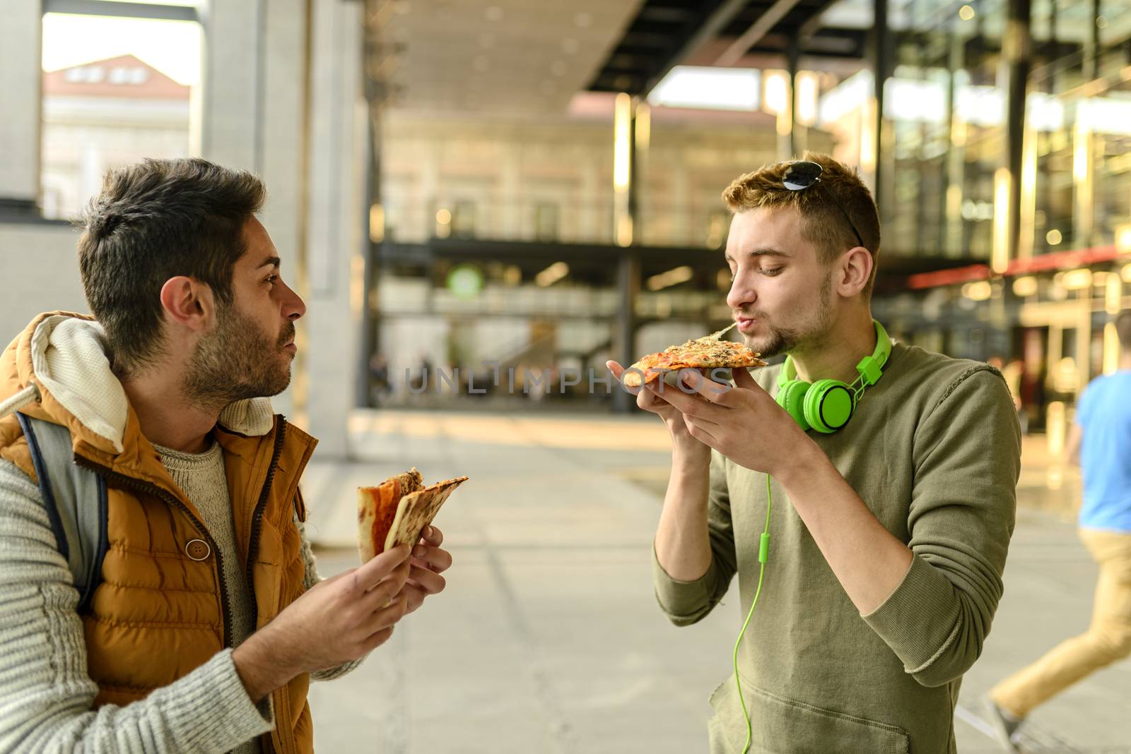 Two young hipsters are enjoying a snack in the city street