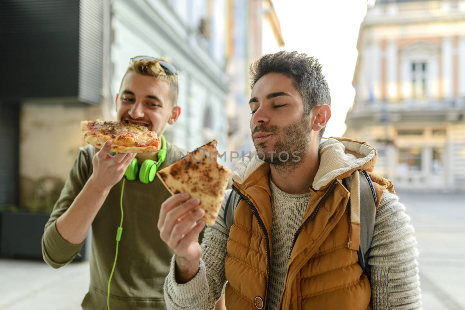 Two young hipsters are enjoying a snack in the city street