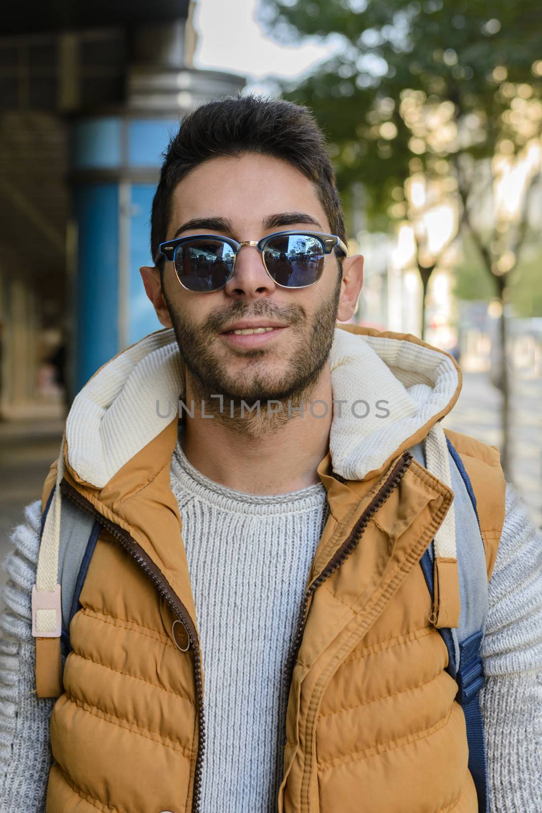 Portrait of a young hipster in orange jacket walking down the street