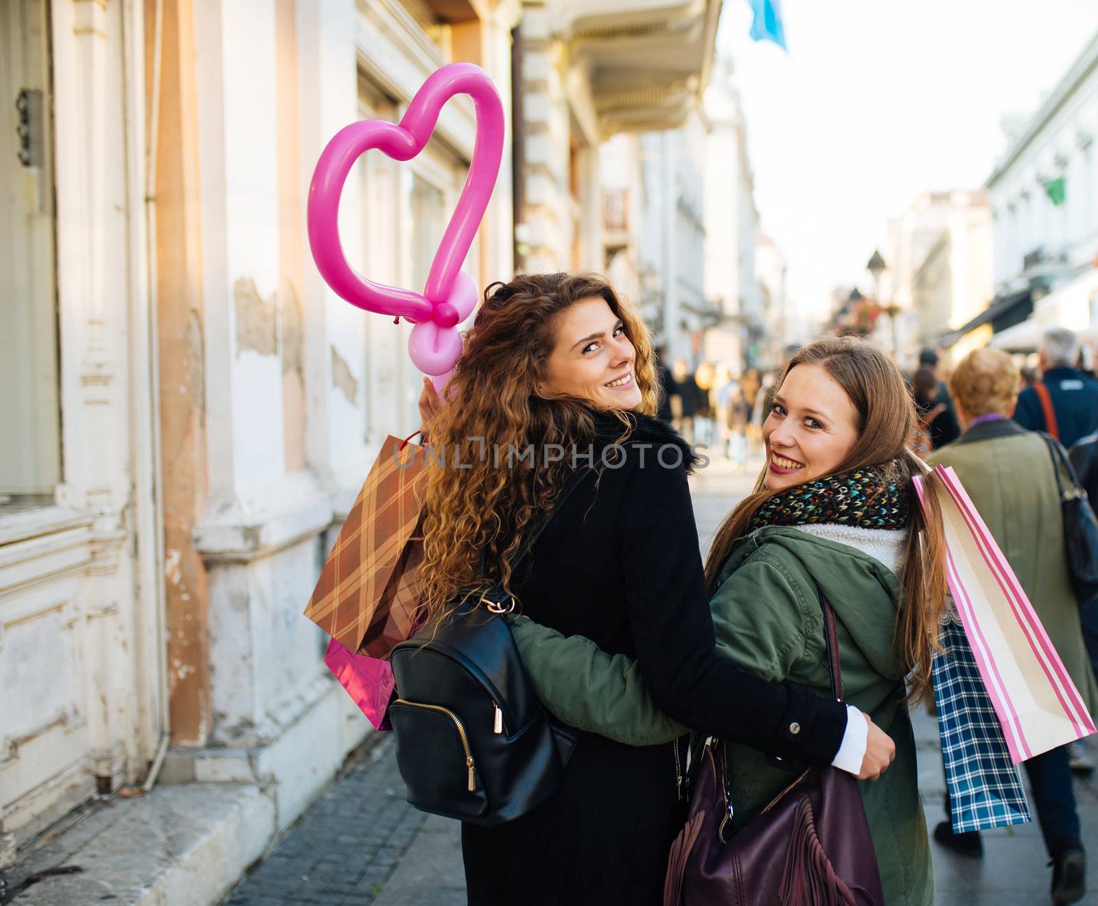 Two attractive young women is satisfied with shopping and walking down the street