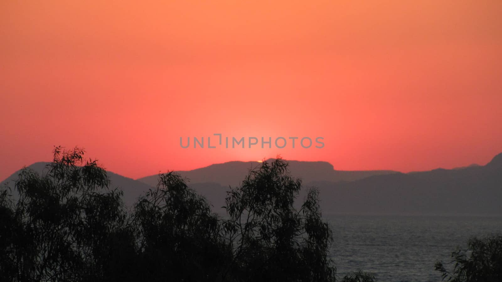 Beautiful dramatic sunset in the mountains. Landscape with sun light shining through orange clouds