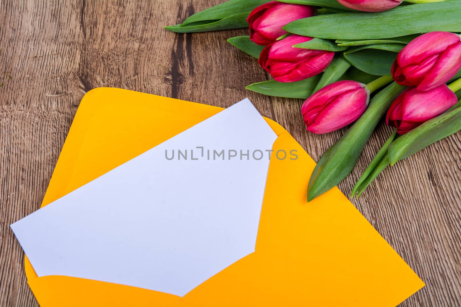 Pink envelope with tulips on a wooden table