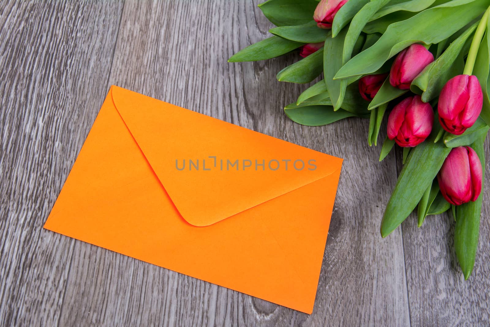 Pink envelope with tulips on a wooden table