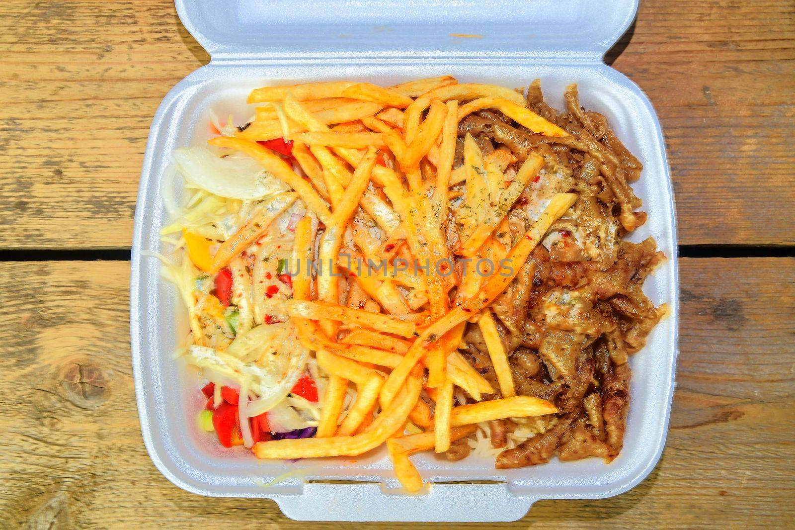 Lunch Box: kebabs, fries and fresh salad in tray. Close-up on the table. Unhealthy food concept. 